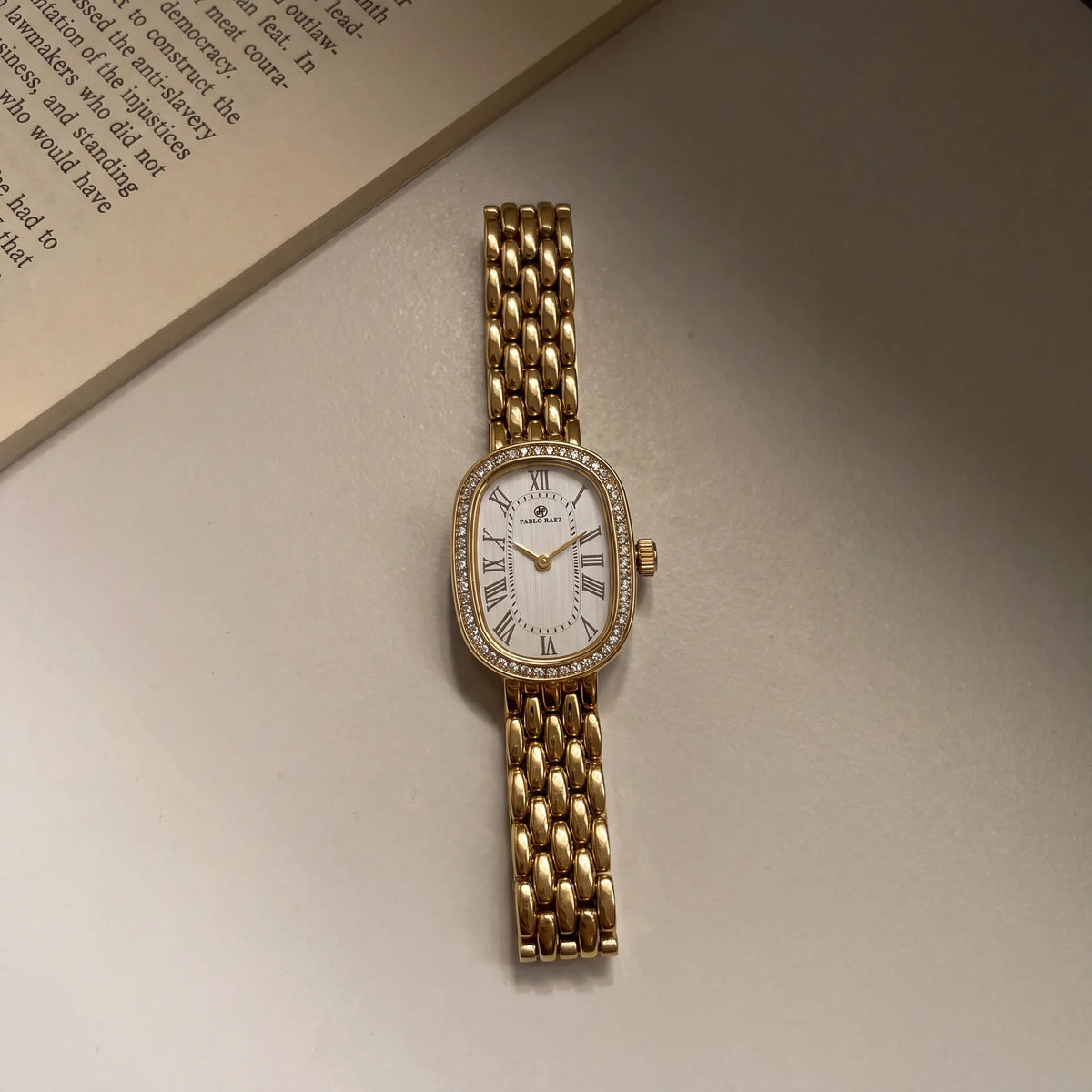 Belgrave 21mm gold women's watch resting on an open book #color_gold